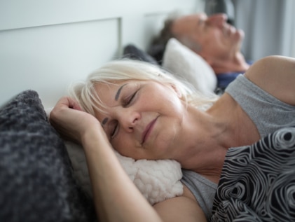 Senior lady sleeping in comfortable bed with husband
