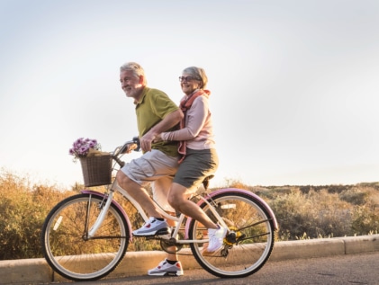 two people enjoying senior living today on a bicycle with flowers