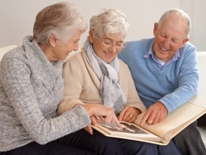 older people smiling at a photo album
