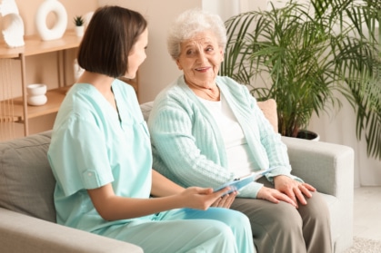Smiling senior woman talking with a caregiver, highlighting emotional support and connection in a senior living community.