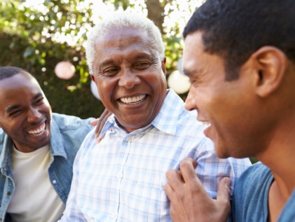 Senior father smiling with adult sons outdoors on Father’s Day.