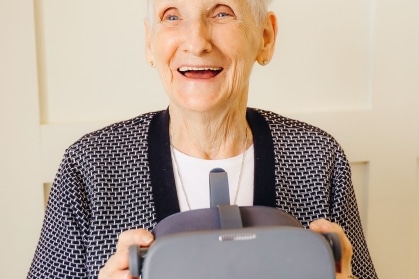 Happy elderly woman holding a virtual reality headset device