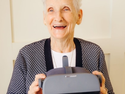 Happy elderly woman holding a virtual reality headset device