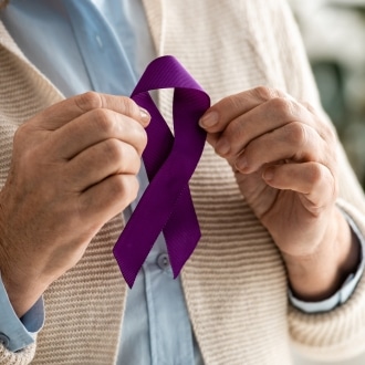 Senior holding a purple Alzheimer's awareness ribbon in support of memory care and advocacy