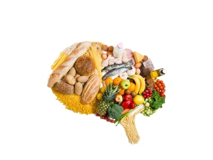 Silhouette of human brain made of brain-healthy foods for seniors, including leafy greens, fatty fish, berries, walnuts, whole grains, and vegetables.